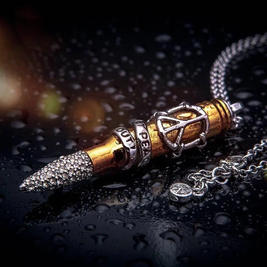 Signature pendant with a peace symbol, resting on a rain-speckled surface